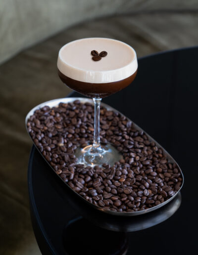 Cocktail Espresso Martini auf einem schwarzen Tisch mit einer Sitzgarnitur im Hintergrund im B1 Rooftop Bistro Basel.